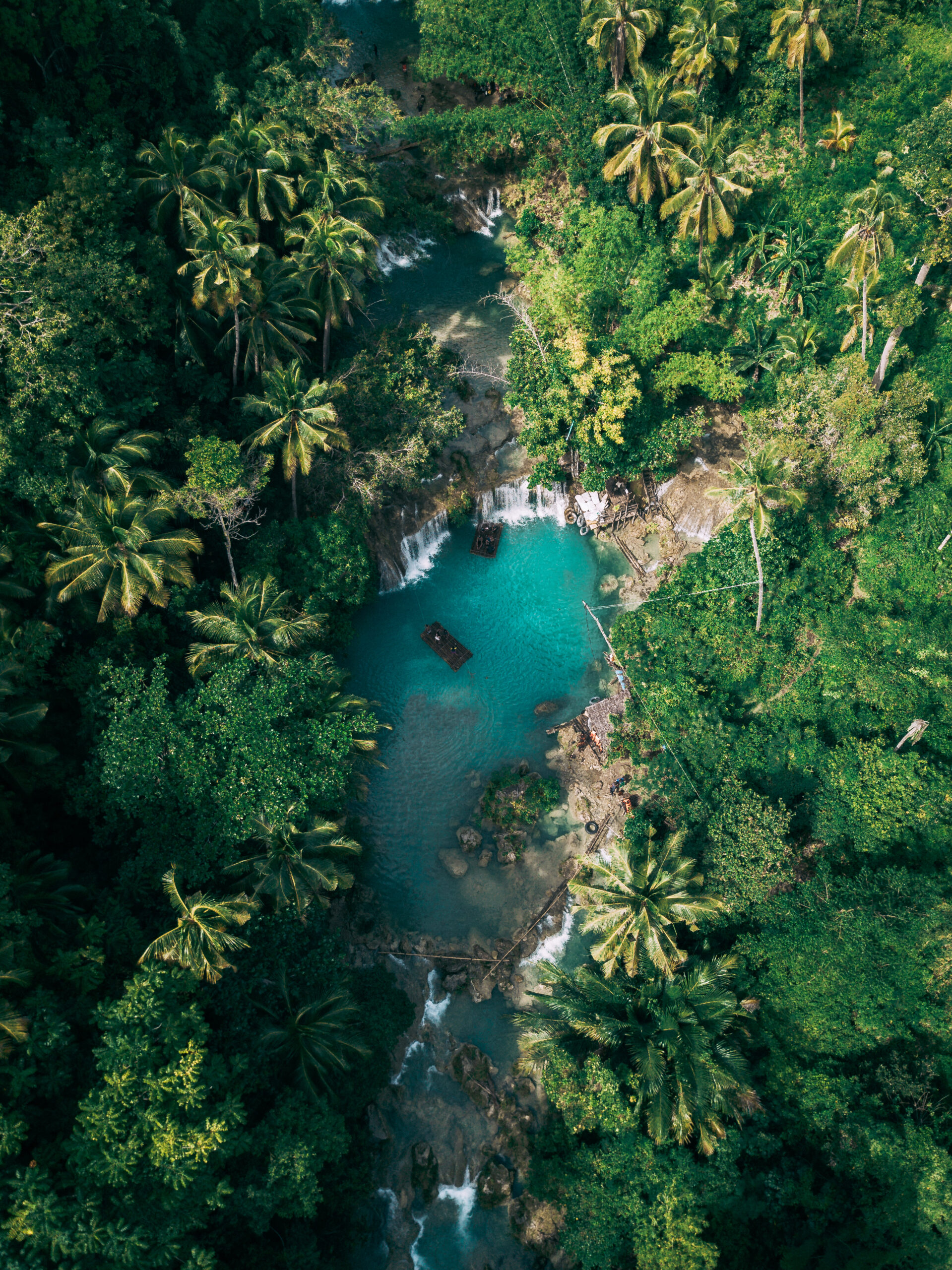 beautiful waterfall streaming into river surrounded by greens 1 scaled.jpg